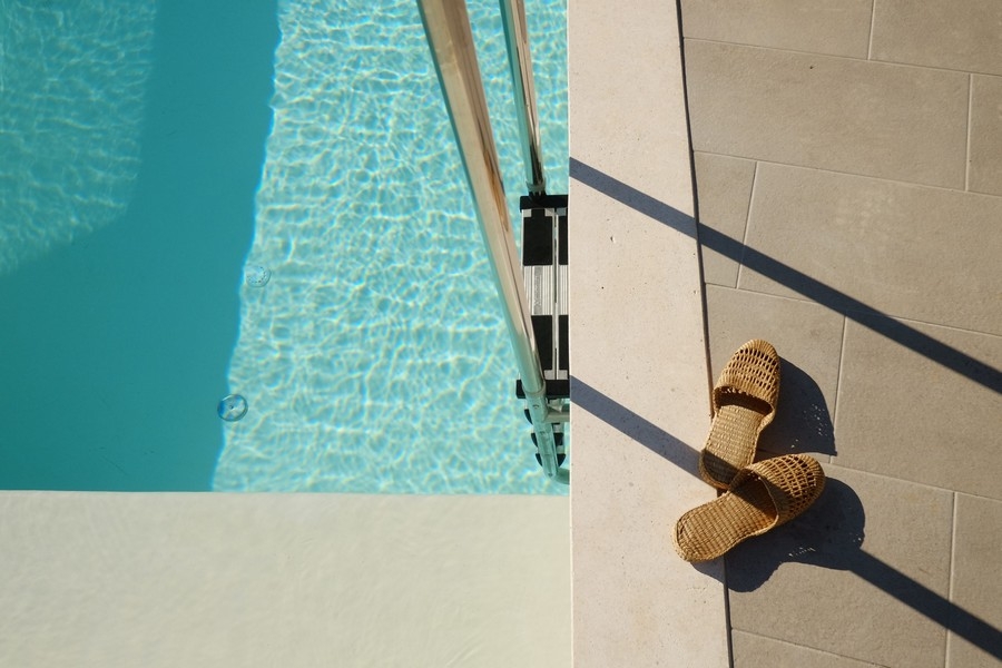 Szczegóły basenu ze światłem słonecznym i sandałami