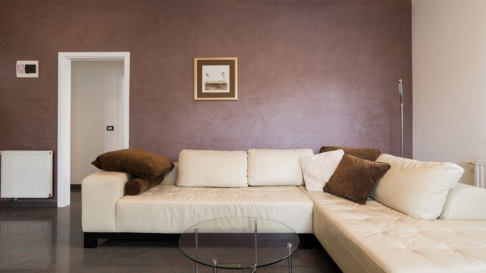 Pokój dzienny z jasną skórzaną kanapą i szklanym stołem