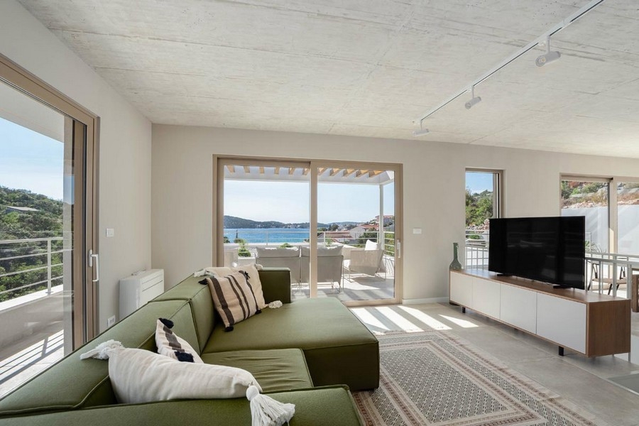 Pokój dzienny z sofą i wyjściem na taras z widokiem na morze