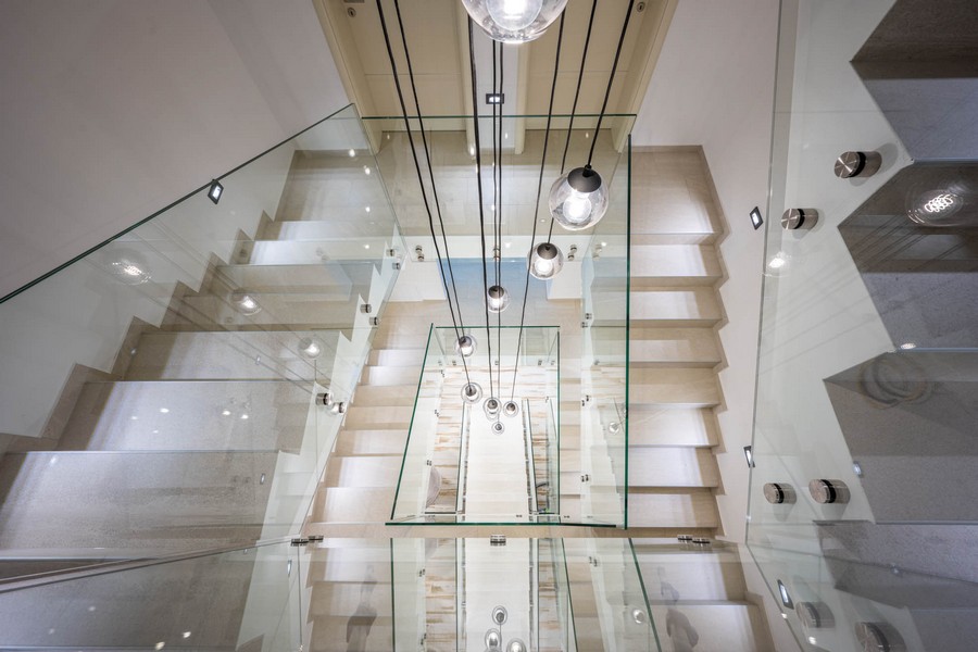 Schody ze szklanymi balustradami i designerskimi światłami