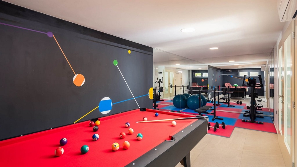 Sala rekreacyjno-fitnessowa ze stołem bilardowym i sprzętem do ćwiczeń
