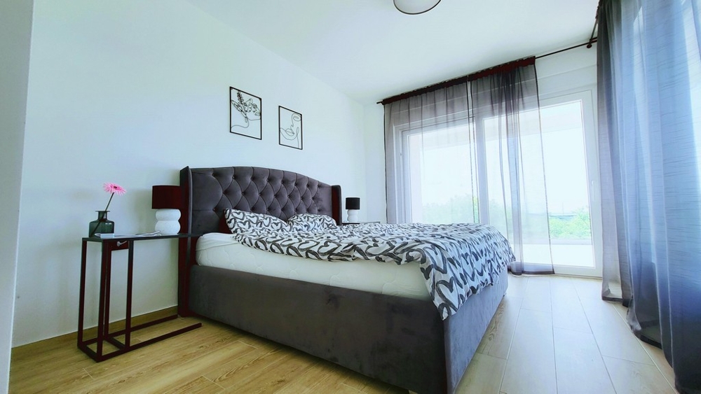 Jasna sypialnia z podwójnym łóżkiem i wyjściem na balkon