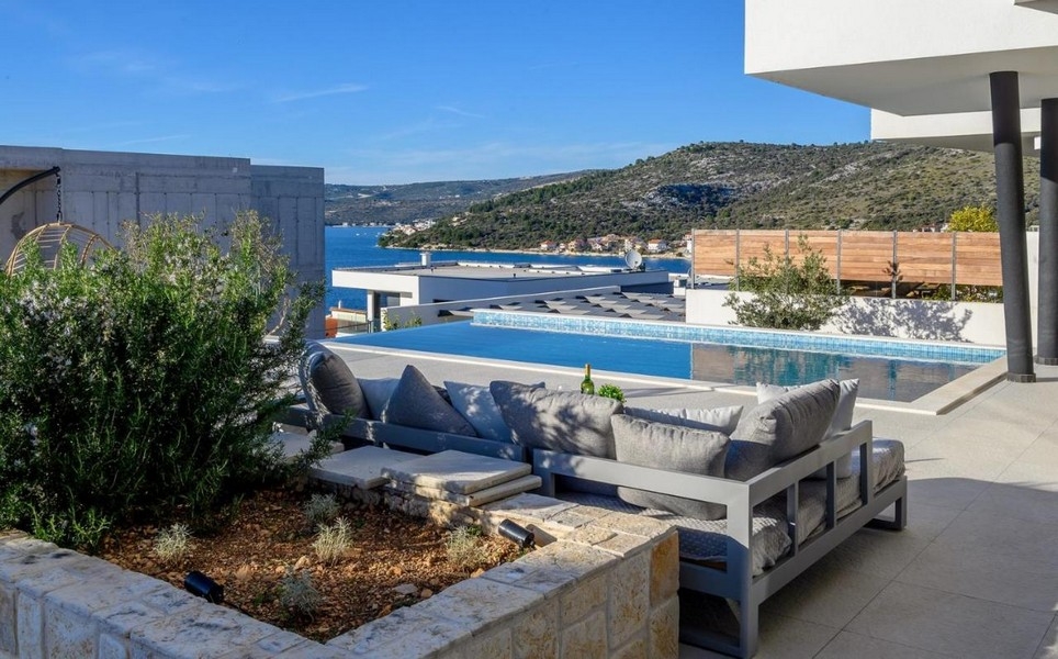 Taras z częścią wypoczynkową i basenem bez krawędzi, widok na morze