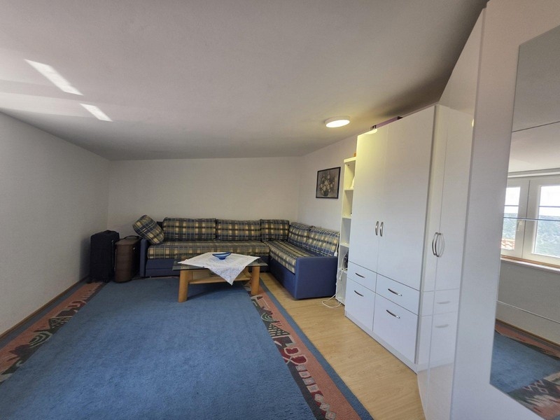 Pokój dzienny z narożną sofą, dywanem i szafką