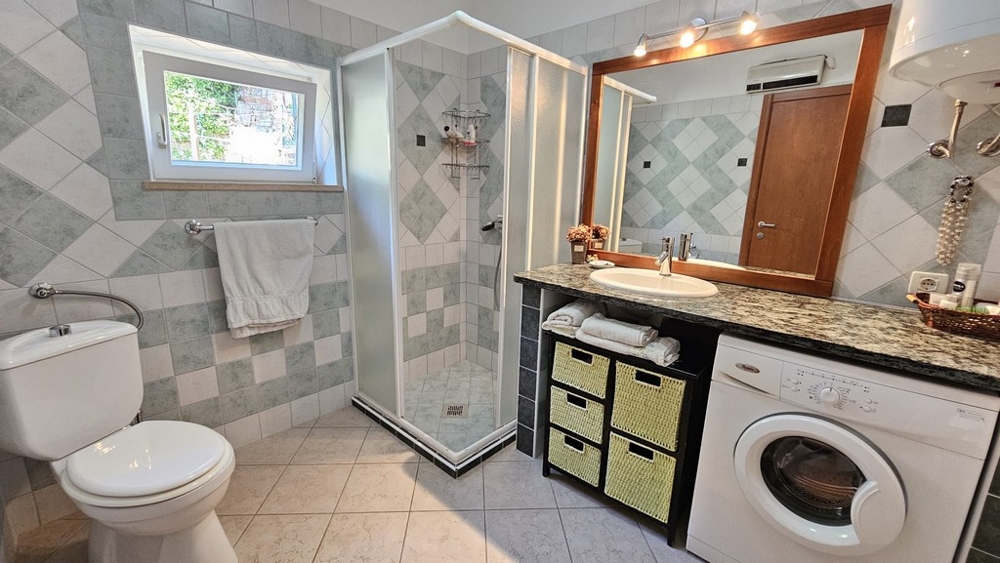 Łazienka z prysznicem, umywalką i pralką