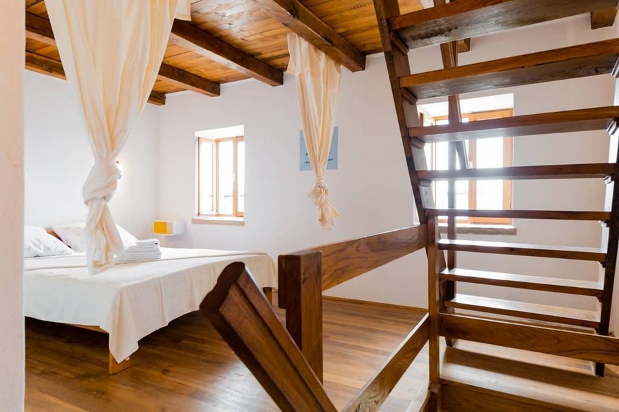 Sypialnia z drewnianymi podłogami, schodami i naturalnym światłem