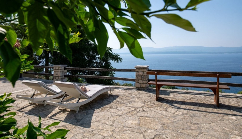 Kamienny taras z leżakami i panoramicznym widokiem na morze