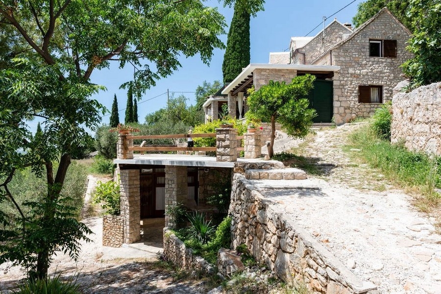 Kamienny dom na zboczu wzgórza z ogrodem i tarasem