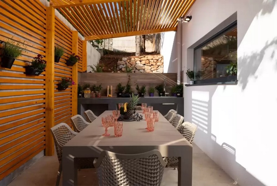 Zadaszona kuchnia letnia ze stołem jadalnym i pergolą