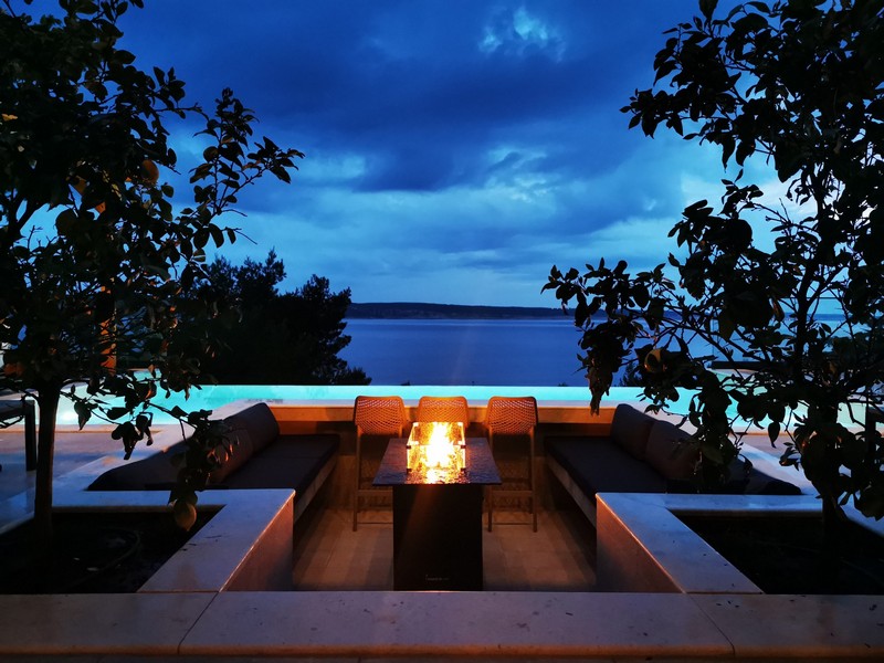 Salon z miejscem na ognisko i widokiem na morze w nocy