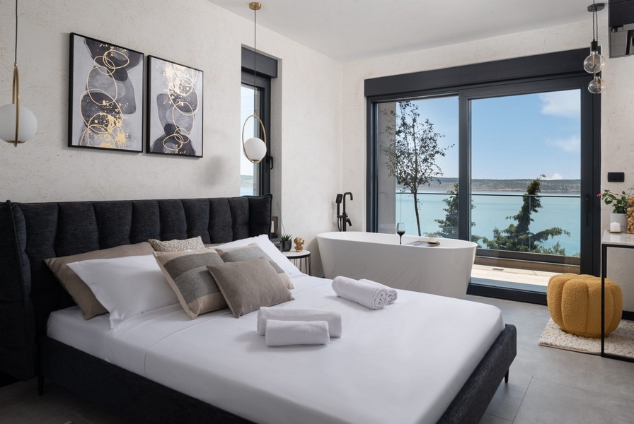 Sypialnia z podwójnym łóżkiem, wolnostojącą wanną i widokiem na morze