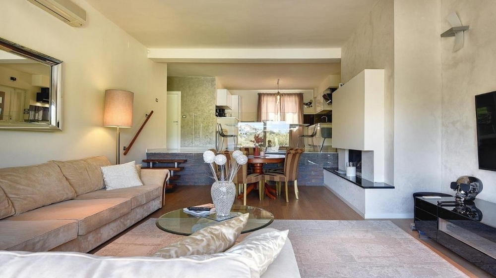 Jasny salon z sofą, kominkiem i przylegającą jadalnią