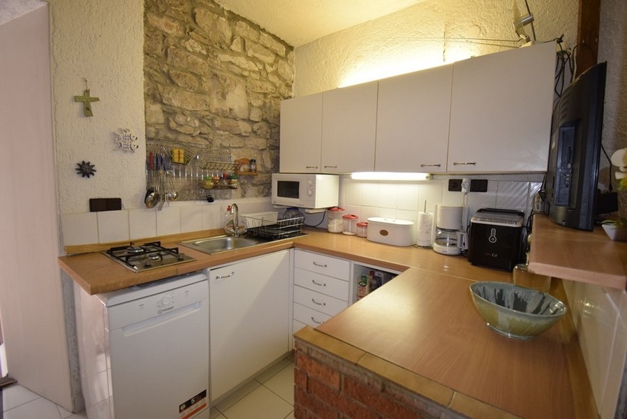 Kuchnia z wyposażonym aneksem kuchennym i kamienną ścianą