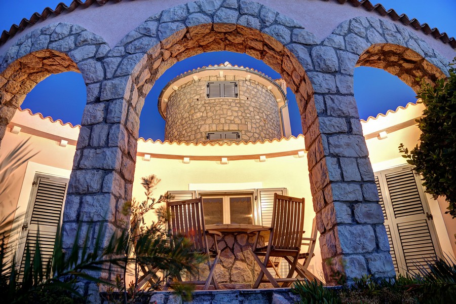 Kamienne arkady i okrągła wieża z tarasem oświetlonym w nocy