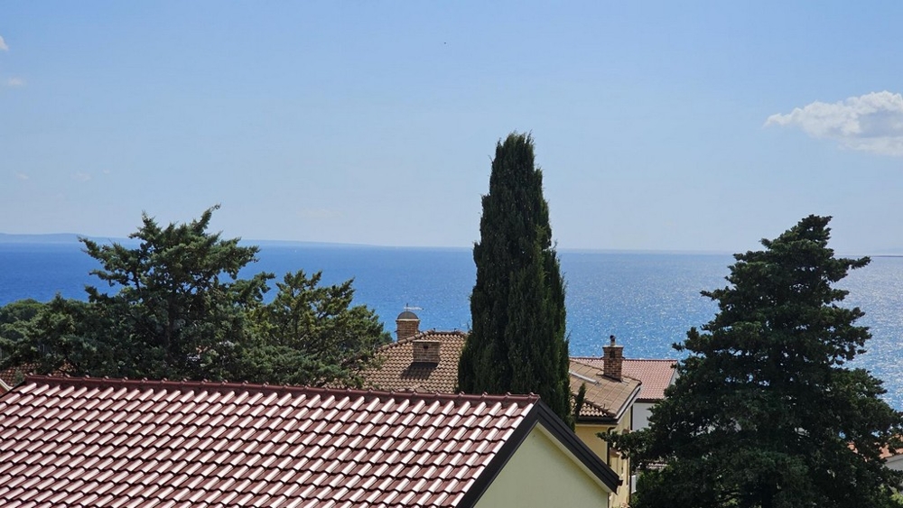 Widok na morze z balkonu na dachy i drzewa