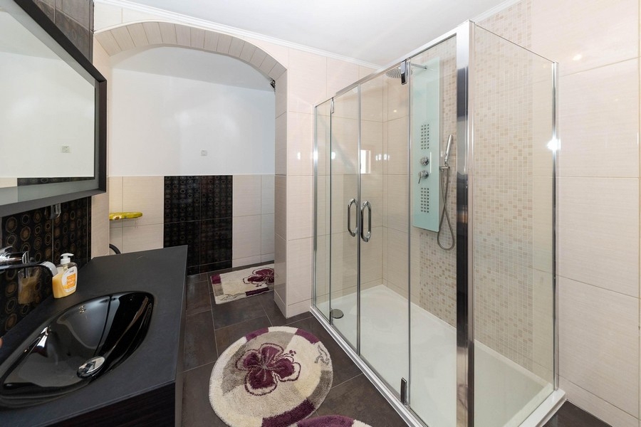 Nowoczesna łazienka z dużym, szklanym prysznicem i ciemną toaletką