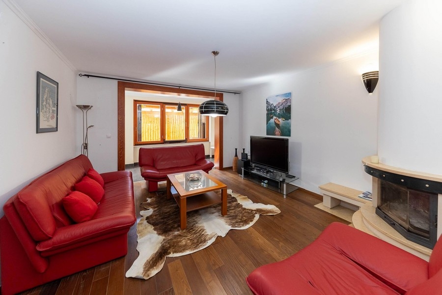 Pokój dzienny z czerwonymi skórzanymi sofami i kominkiem