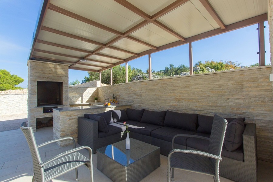 Zadaszony taras z częścią wypoczynkową i kominkiem do grillowania