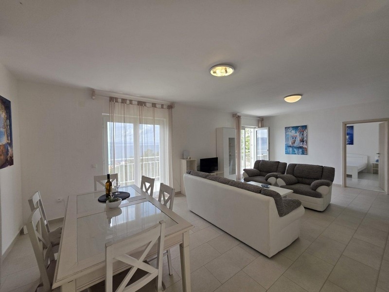 Pokój dzienny z sofą i jadalnią, widok na morze