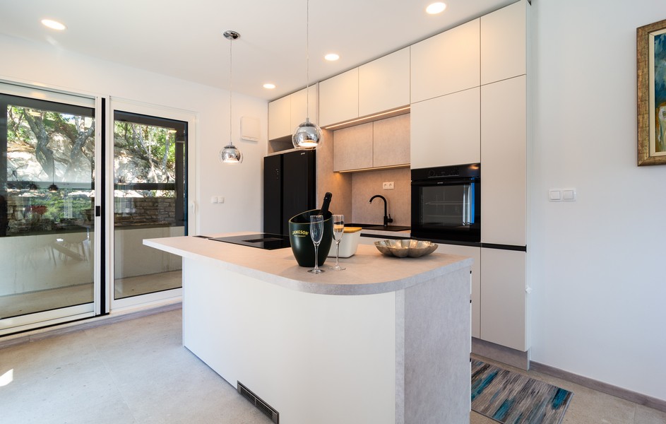 Nowocześnie wyposażona kuchnia z wyspą kuchenną i wyjściem na taras