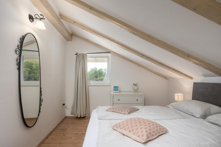 Przytulna sypialnia na poddaszu z drewnianymi belkami