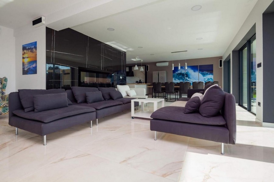 Przestronny salon z oknami sięgającymi od podłogi do sufitu i nowoczesnymi meblami