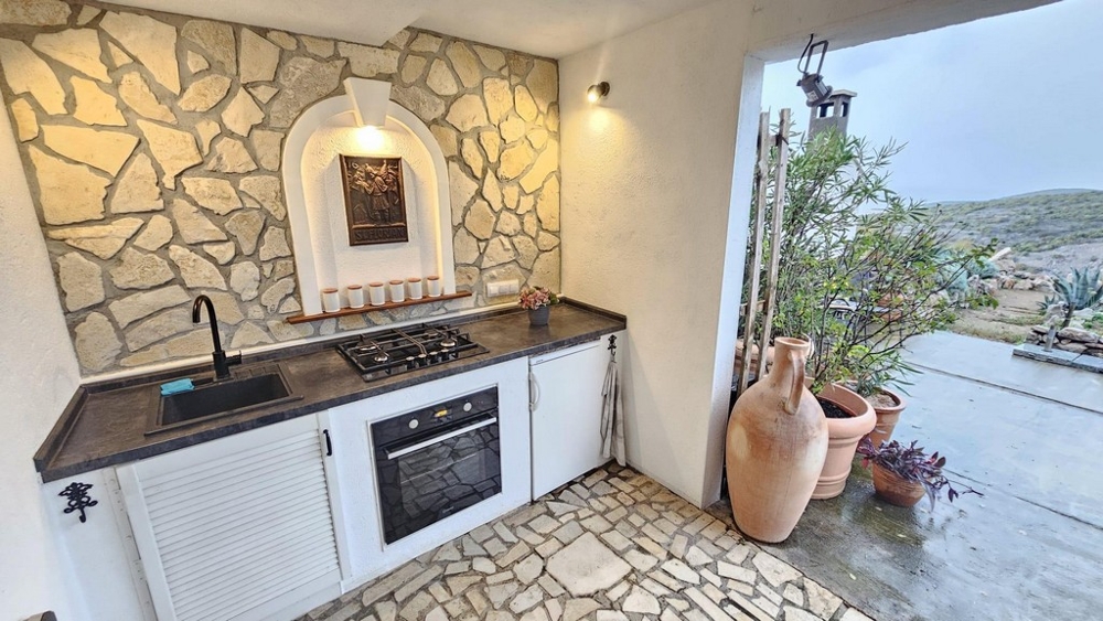 Zadaszona letnia kuchnia z kamienną ścianą i kuchenką gazową