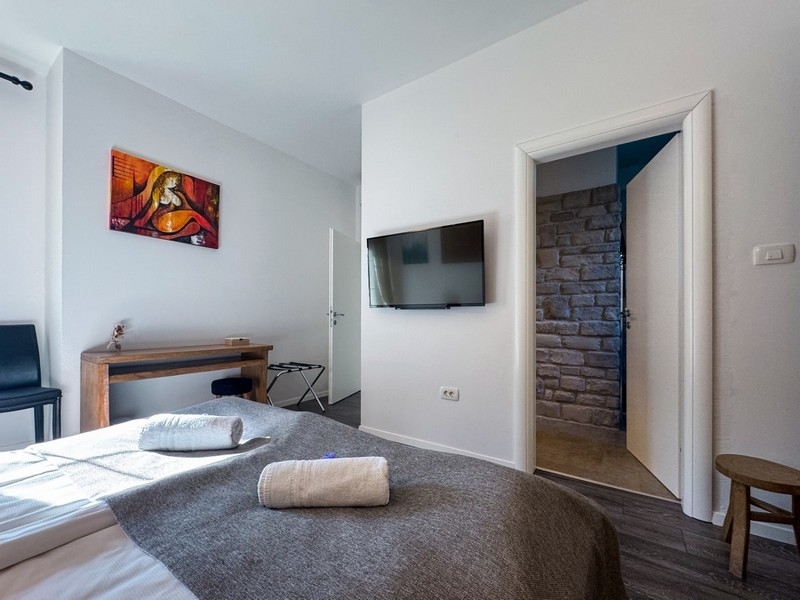 Jasna sypialnia z telewizorem i kamiennymi detalami ściennymi