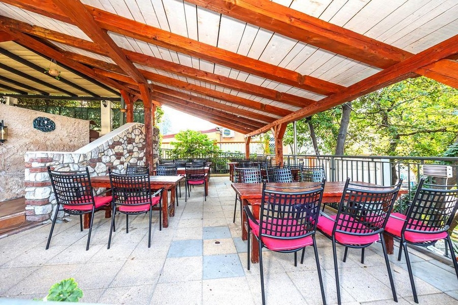 Zadaszony taras zewnętrzny z drewnianym dachem i miejscami do siedzenia w restauracji