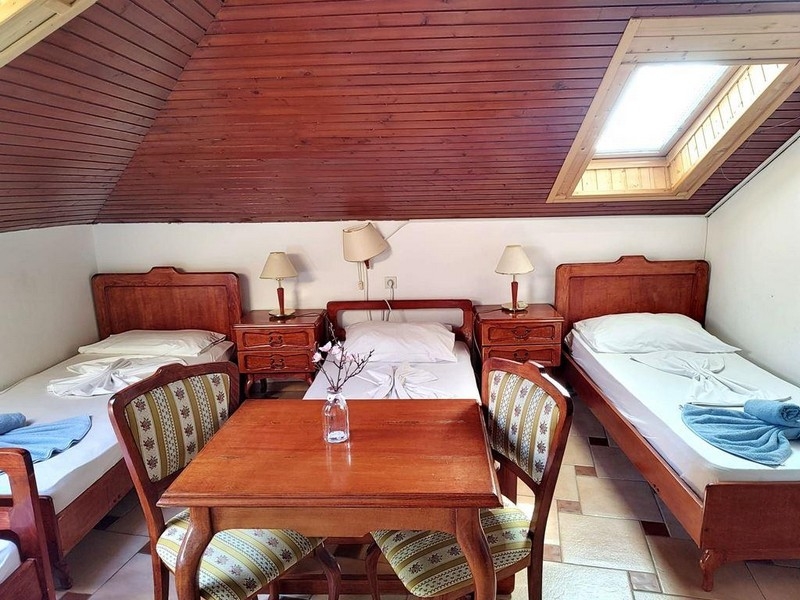 Pokój trzyosobowy na poddaszu z drewnianymi meblami