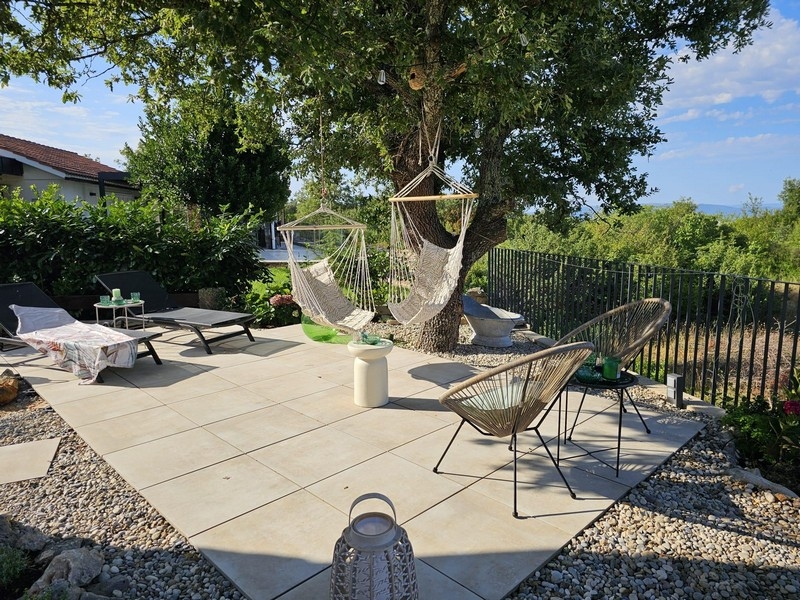 Taras słoneczny z wiszącymi krzesłami i widokiem na ogród