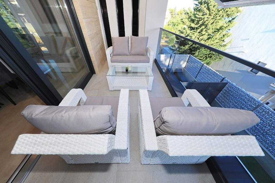 Część wypoczynkowa na balkonie ze szklaną balustradą