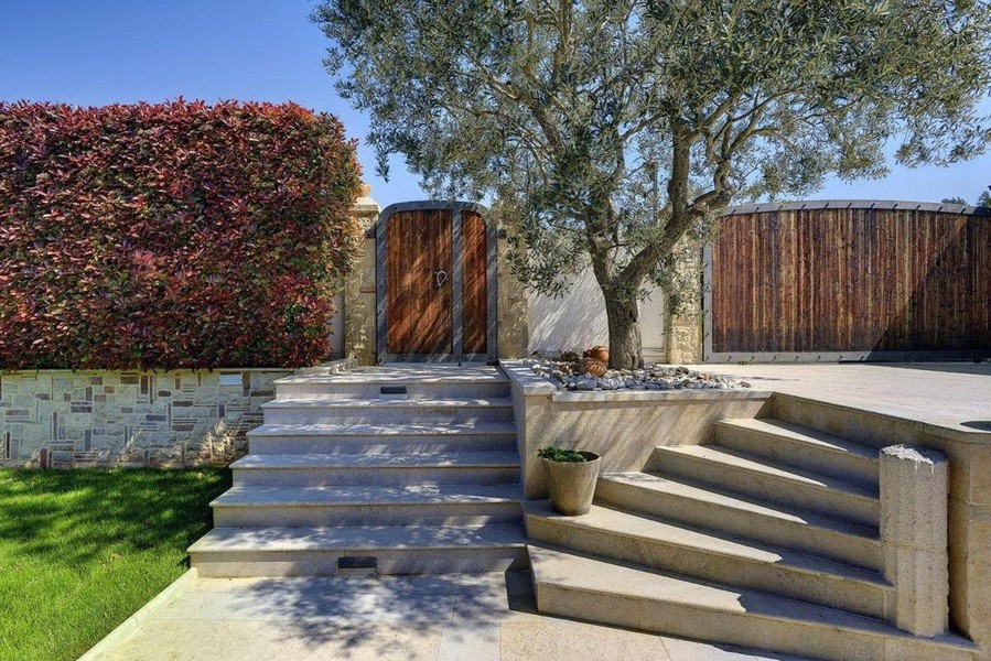 Obszar wejściowy ze schodami, drewnianą bramą i drzewem oliwnym