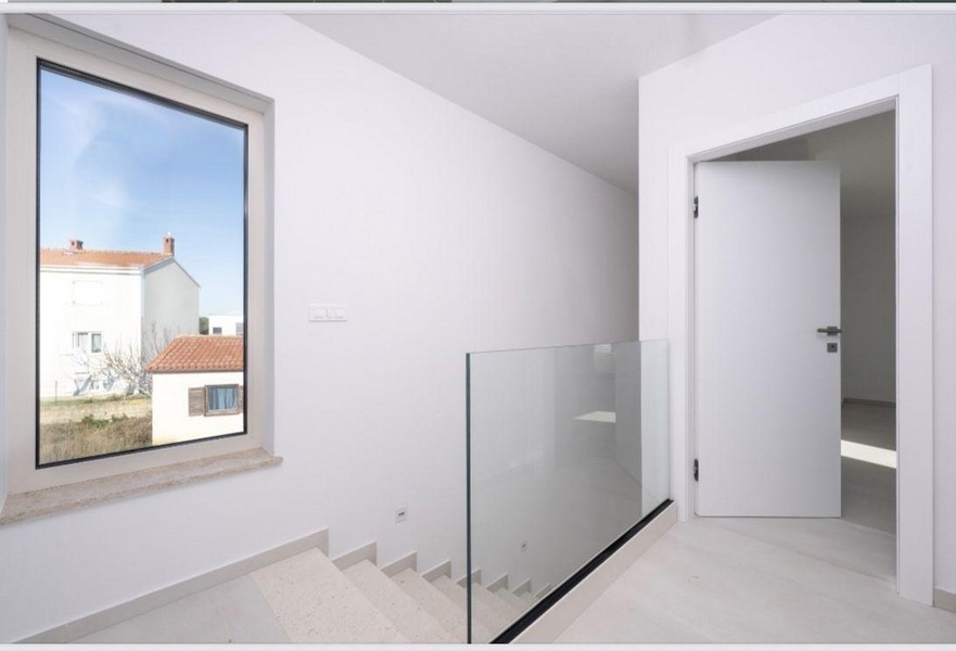 Na piętrze klatka schodowa ze szklanymi balustradami