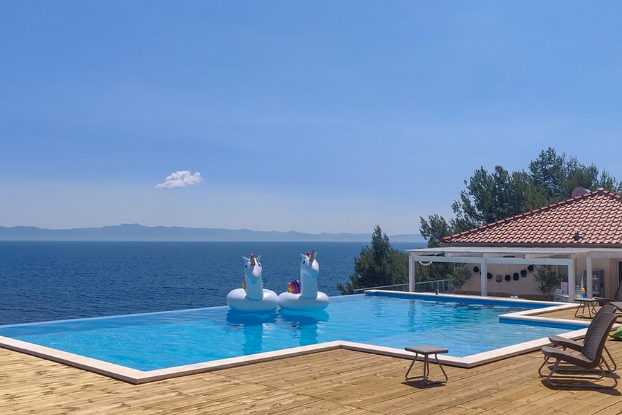 Basen typu infinity z widokiem na morze i przestronnym drewnianym tarasem