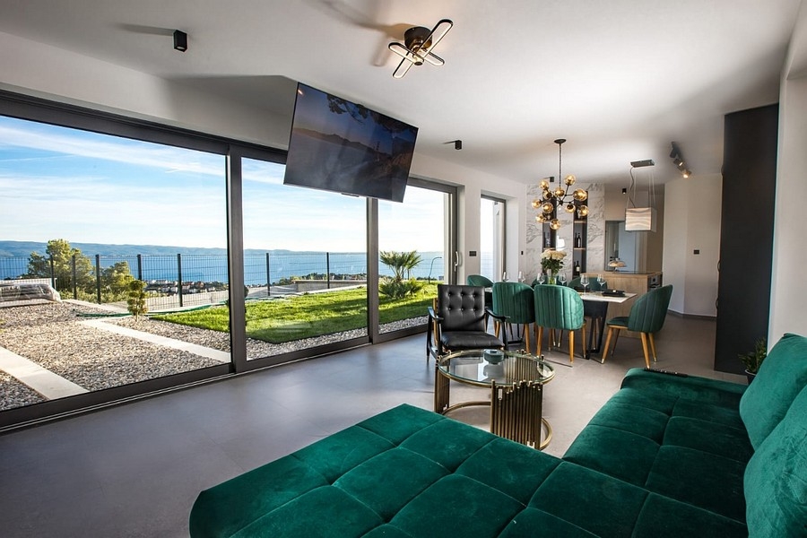 Nowoczesna część dzienna z dużymi szklanymi frontami i widokiem na morze