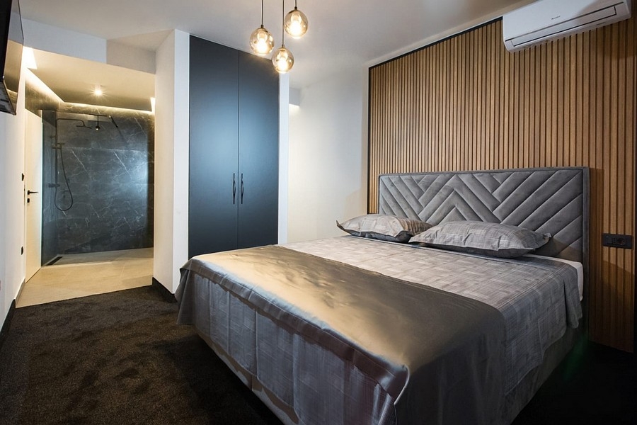 Sypialnia z drewnianą ścianą panelową i zintegrowaną łazienką z prysznicem