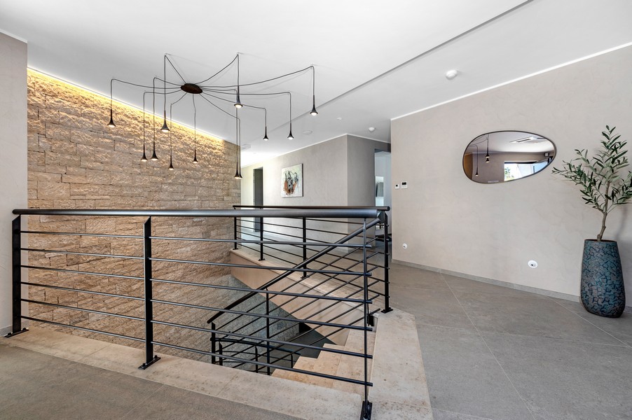 Galeria na piętrze z nowoczesnymi balustradami i designerskimi lampami