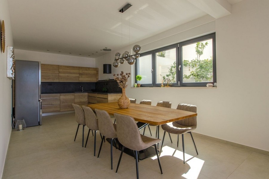 Jadalnia z dużym drewnianym stołem i nowoczesnym oświetleniem