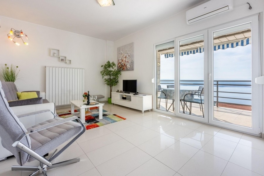 Pokój dzienny z wyjściem na balkon i widokiem na morze