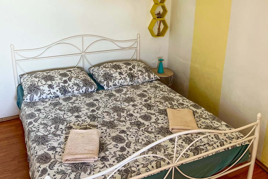 Sypialnia z metalowym łóżkiem i stolikiem nocnym