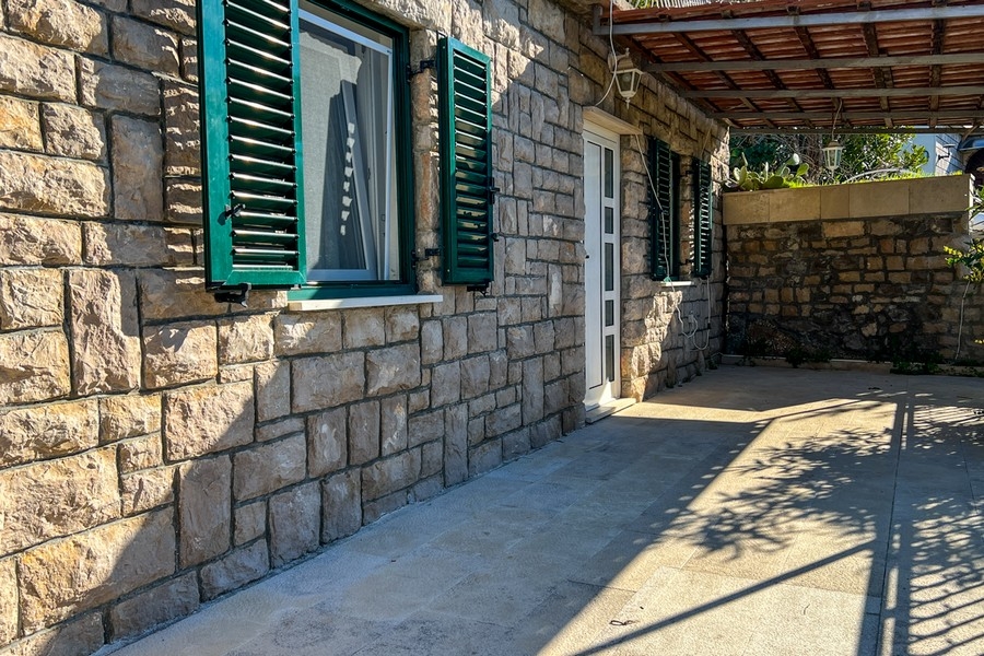 Kamienny taras z wyjściem na dom i zielonymi okiennicami