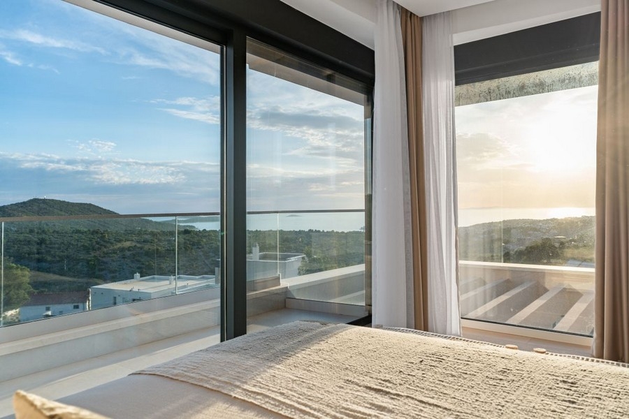 Sypialnia z oknami sięgającymi od podłogi do sufitu i panoramicznym widokiem na morze