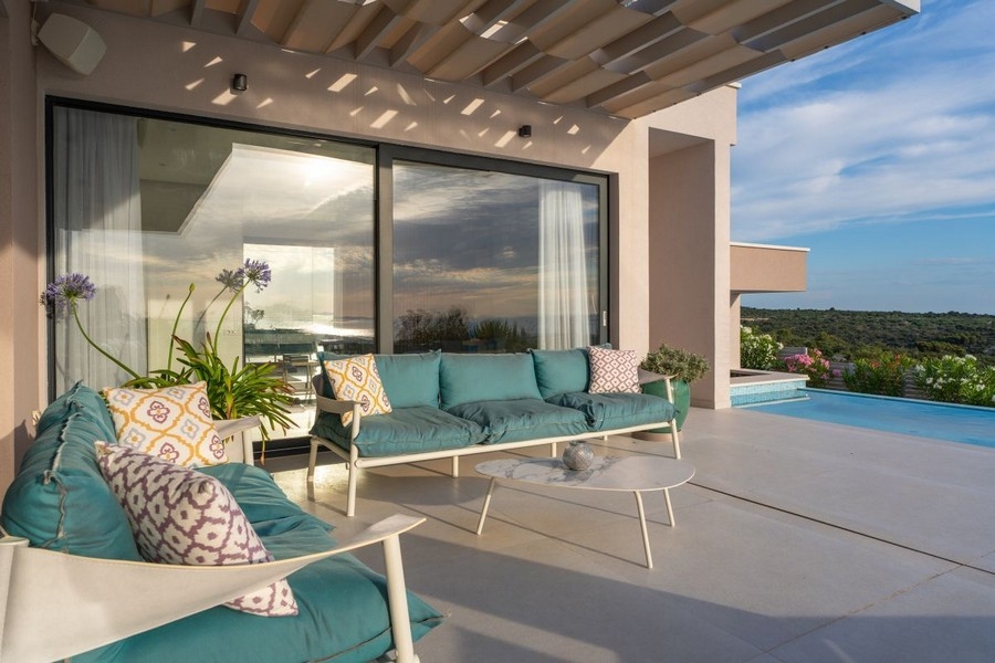 Zadaszony taras z salonem i widokiem na basen i morze
