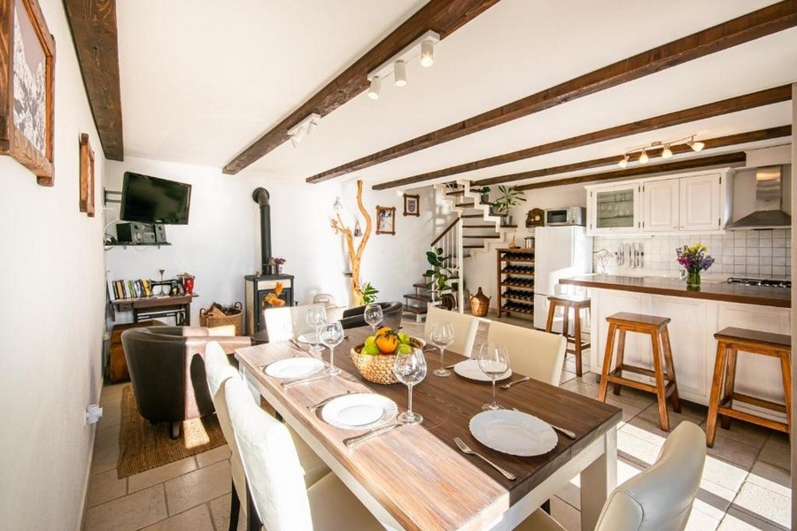 Część dzienna z drewnianymi belkami, kominkiem i kuchnią