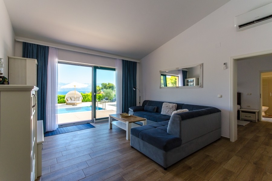 Część dzienna z sofą i drzwiami tarasowymi na basen