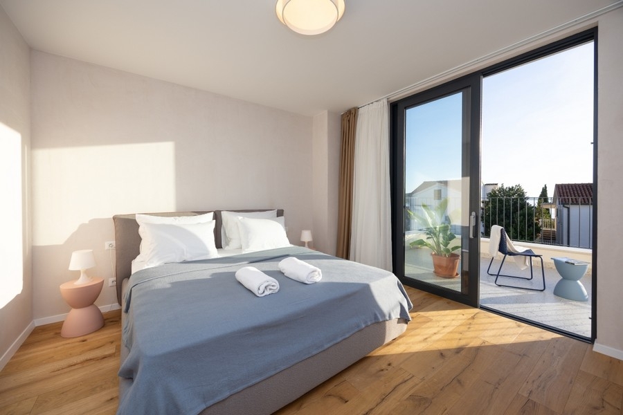 Sypialnia z podwójnym łóżkiem i dostępem do tarasu Villi H3837 w Rogoznicy w Chorwacji.