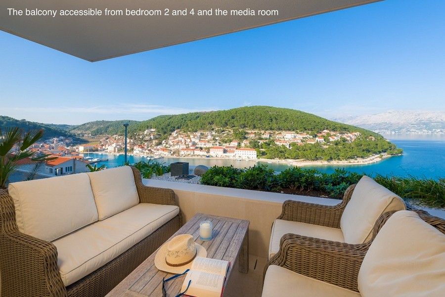 Zadaszony balkon z częścią wypoczynkową i widokiem na zatokę i miasto