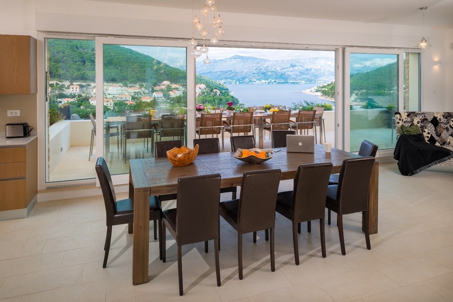 Część dzienna z dużym stołem jadalnym i panoramicznymi oknami z widokiem na morze