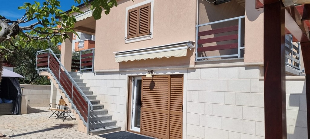 Elewacja domu z balkonem, markizami i osobnymi wejściami do mieszkań